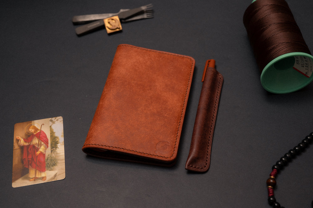 Sienna full grain leather pocket journal cover closed, beside its matching dark Tobacco leather pen sleeve