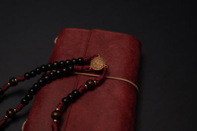 Close-up of the brass St. Benedict centerpiece medal and burgundy paracord knotting on The Protector rosary